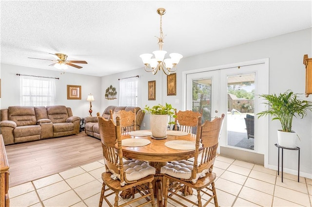 dining room with ceiling fan with notable chandelier, light tile patterned floors, a textured ceiling, and french doors