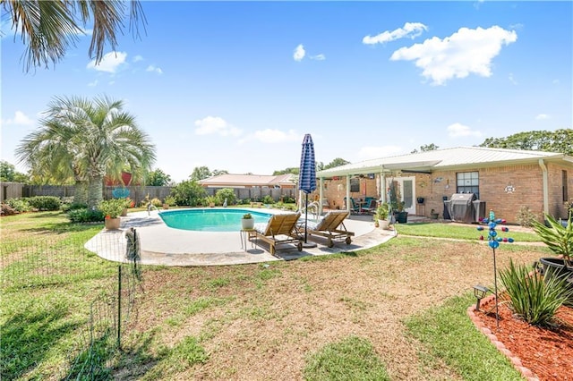 view of pool with a lawn, grilling area, and a patio area