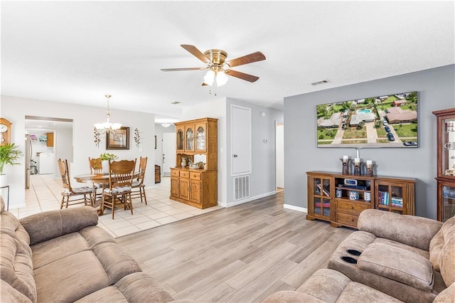 living room featuring washer / clothes dryer, ceiling fan with notable chandelier, and light wood-type flooring