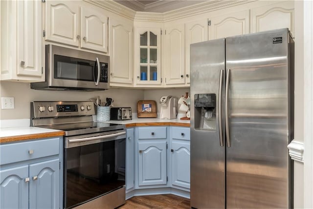 kitchen with blue cabinetry, stainless steel appliances, dark wood-type flooring, and white cabinetry