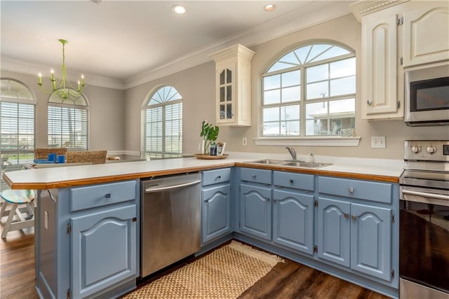 kitchen with white cabinetry, hanging light fixtures, dark wood-type flooring, stainless steel appliances, and a chandelier