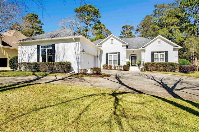 view of front of house featuring an attached garage, driveway, a front yard, and stucco siding