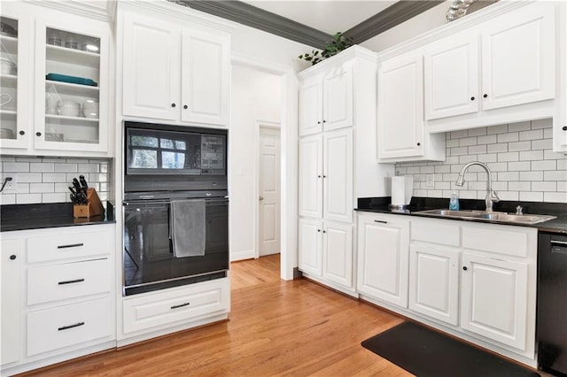 kitchen with dark countertops, white cabinets, a sink, and black appliances