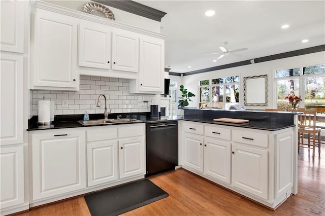 kitchen featuring dark countertops, black dishwasher, a sink, and a peninsula