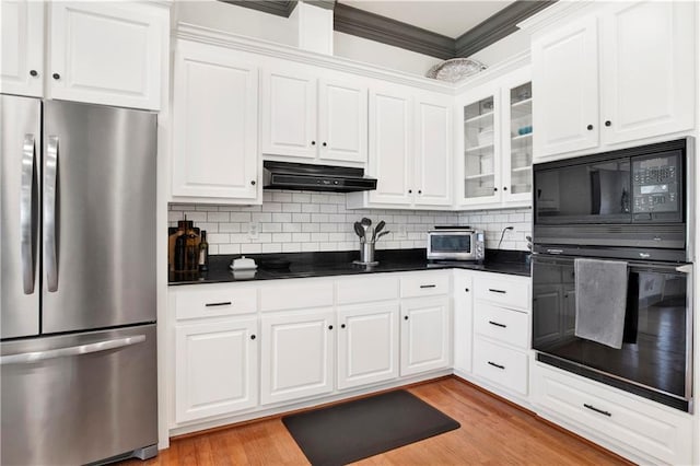 kitchen featuring dark countertops, light wood-style floors, white cabinetry, under cabinet range hood, and black appliances