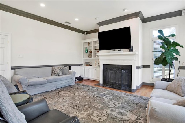 living area featuring recessed lighting, a fireplace with flush hearth, wood finished floors, baseboards, and ornamental molding