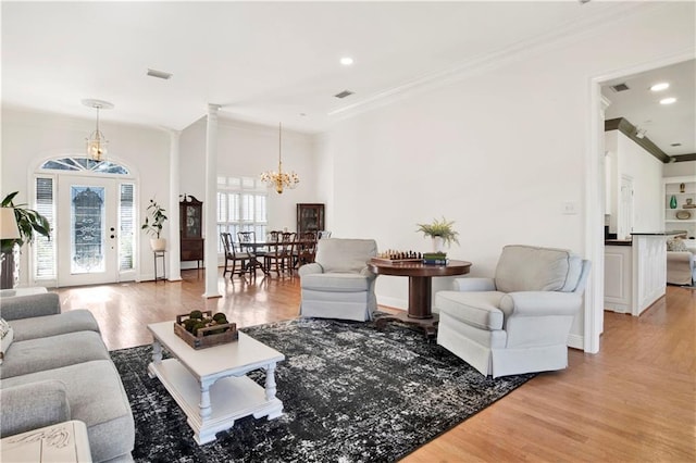 living area with ornamental molding, a chandelier, visible vents, and light wood finished floors