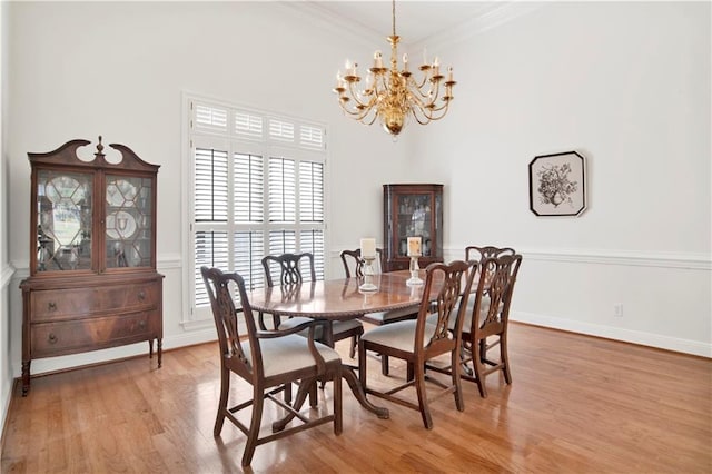 dining room featuring light wood finished floors, baseboards, a chandelier, and crown molding