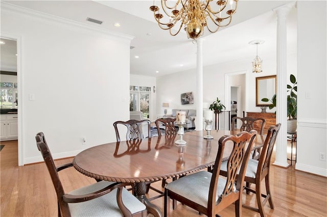 dining room featuring ornate columns, light wood-style flooring, baseboards, and crown molding