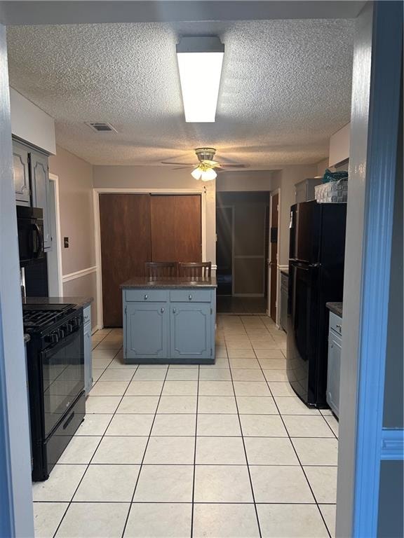 kitchen featuring a textured ceiling, black appliances, light tile patterned floors, and ceiling fan