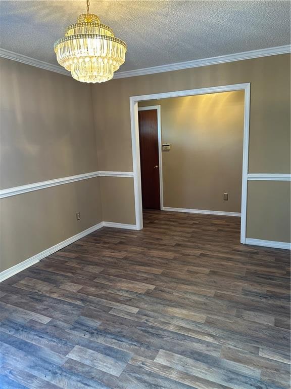 spare room with ornamental molding, dark hardwood / wood-style floors, a notable chandelier, and a textured ceiling