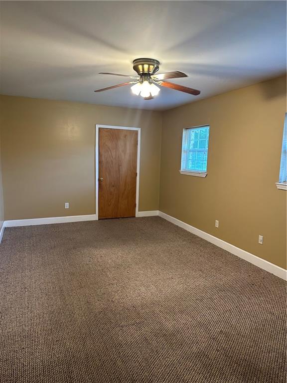 spare room with dark colored carpet and ceiling fan