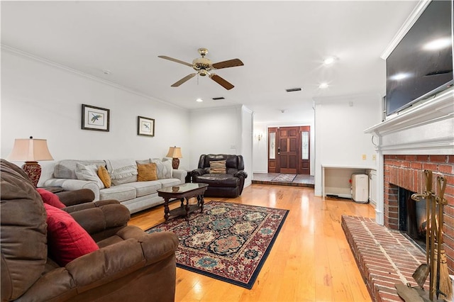 living room with ornamental molding, a brick fireplace, ceiling fan, and light tile floors