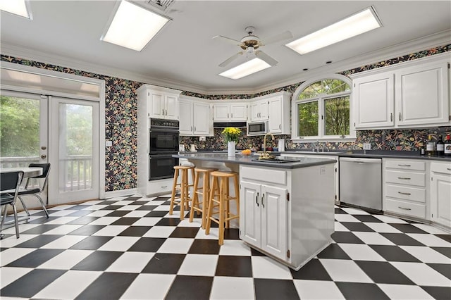 kitchen with ceiling fan, stainless steel appliances, crown molding, and dark tile floors