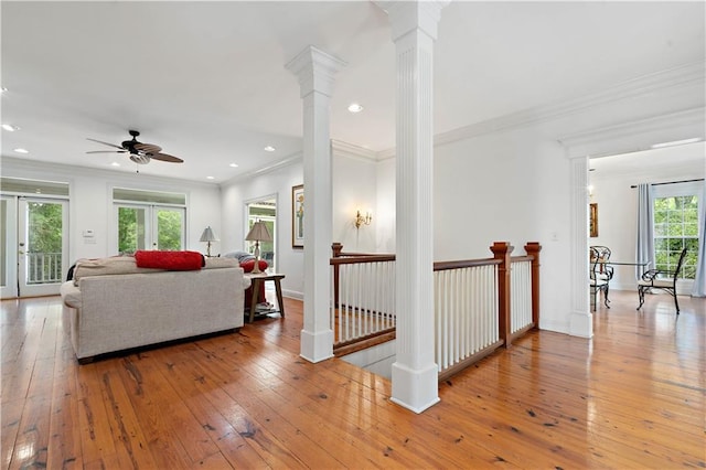 living room featuring light hardwood / wood-style flooring, decorative columns, ceiling fan, and ornamental molding