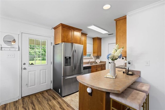 1411 Creola Axis Loop Rd, Axis, AL 36505 - kitchen with stainless steel appliances, a sink, a peninsula, brown cabinets, and a breakfast bar