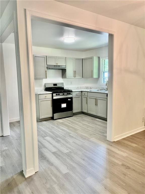 3905 Charmaine Cir E, Mobile, AL 36605 - kitchen featuring stainless steel range with gas cooktop, light wood-style flooring, under cabinet range hood, and light countertops