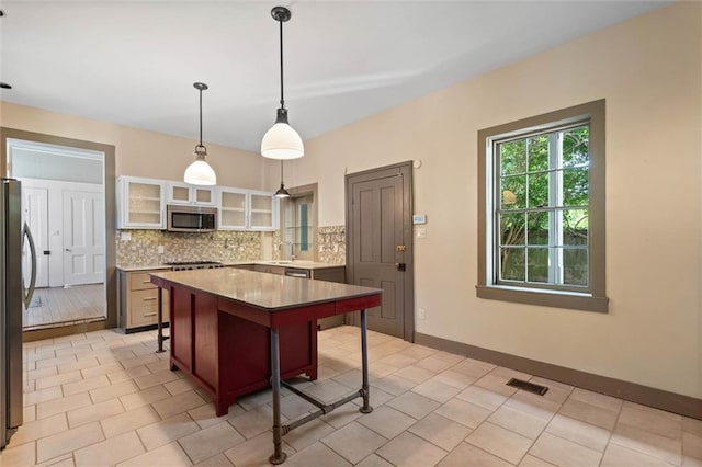 255 N Conception St, Mobile, AL 36603 - kitchen with stainless steel appliances, tasteful backsplash, a breakfast bar area, glass insert cabinets, and a center island