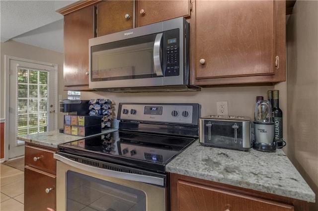 2647 Weems Dr, Mobile, AL 36607 - kitchen with appliances with stainless steel finishes, light tile patterned floors, brown cabinets, and light stone countertops
