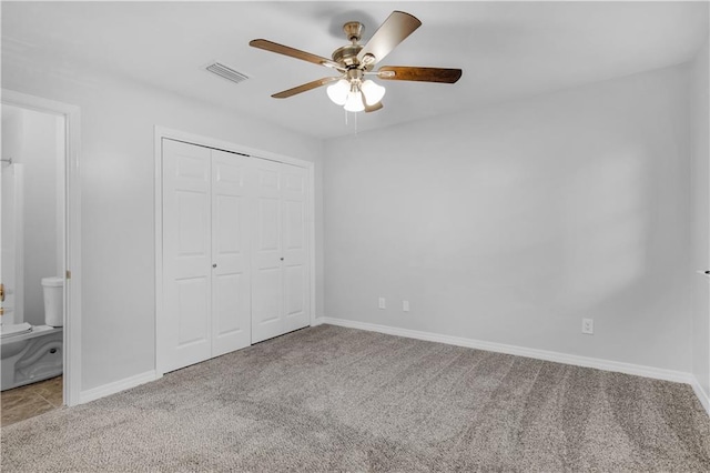 unfurnished bedroom with ensuite bath, ceiling fan, a closet, and light carpet