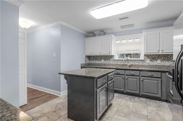 kitchen featuring white cabinets, a center island, ornamental molding, and sink