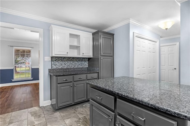 kitchen featuring backsplash, dark stone counters, crown molding, light hardwood / wood-style flooring, and gray cabinets