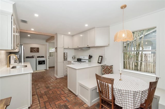 kitchen with visible vents, recessed lighting, white cabinets, white range, and washing machine and dryer