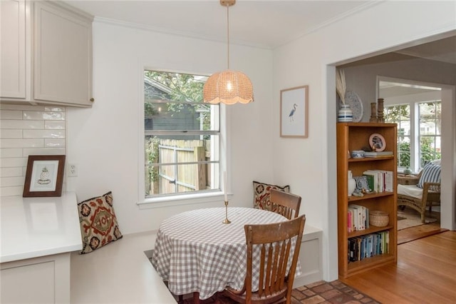 dining area featuring wood finished floors, a healthy amount of sunlight, and ornamental molding