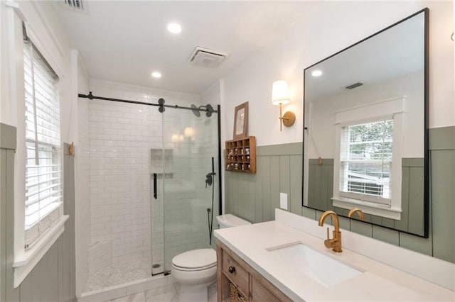 bathroom featuring a stall shower, visible vents, toilet, and a wainscoted wall