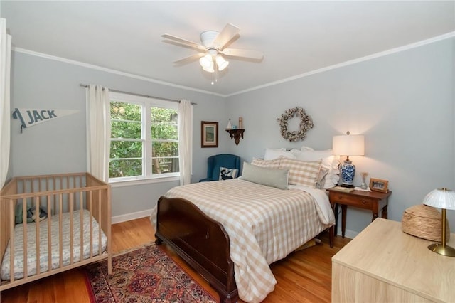 bedroom featuring ceiling fan, baseboards, wood finished floors, and crown molding