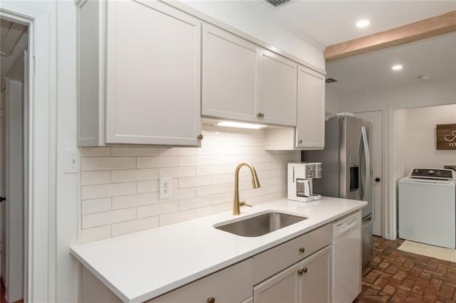 kitchen featuring washer / dryer, recessed lighting, white dishwasher, a sink, and decorative backsplash