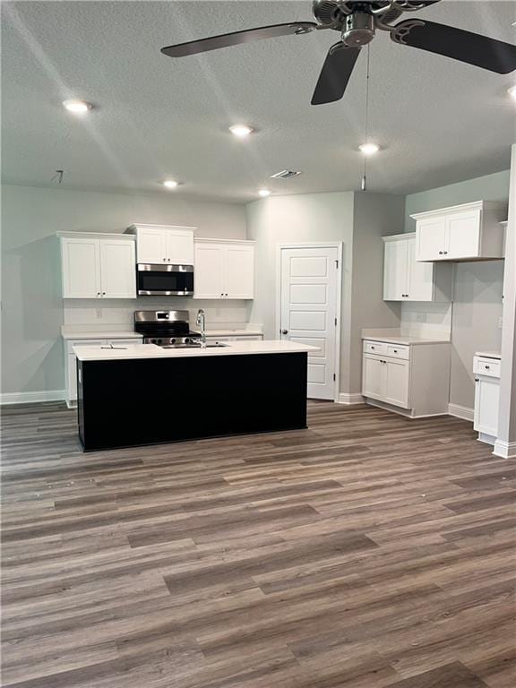 7324 Hawkins Mnr N, Mobile, AL 36695 - kitchen with stainless steel appliances, a ceiling fan, a textured ceiling, dark wood-type flooring, and a center island with sink