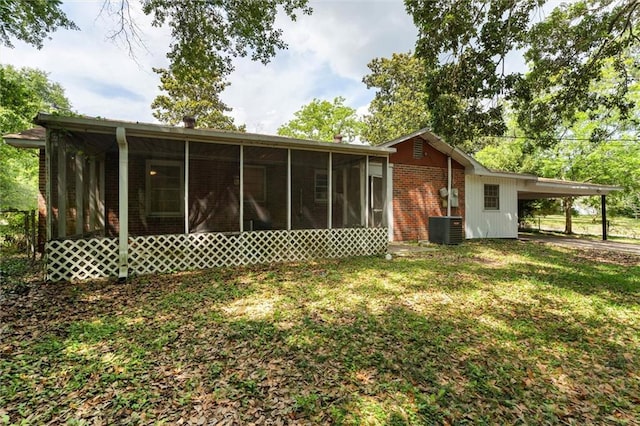 4615 Sunset Dr N, Mobile, AL 36608 - back of house featuring a sunroom, central air condition unit, a lawn, an attached carport, and brick siding