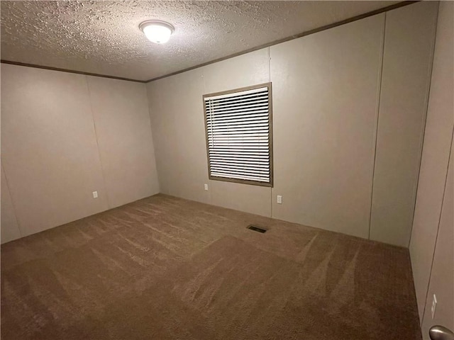 carpeted empty room featuring a textured ceiling