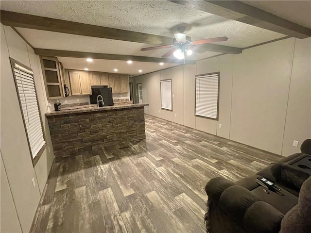 kitchen featuring black refrigerator, beam ceiling, wood-type flooring, stone countertops, and kitchen peninsula