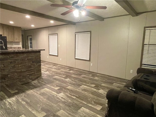 living room with ceiling fan, beam ceiling, dark hardwood / wood-style flooring, and a textured ceiling