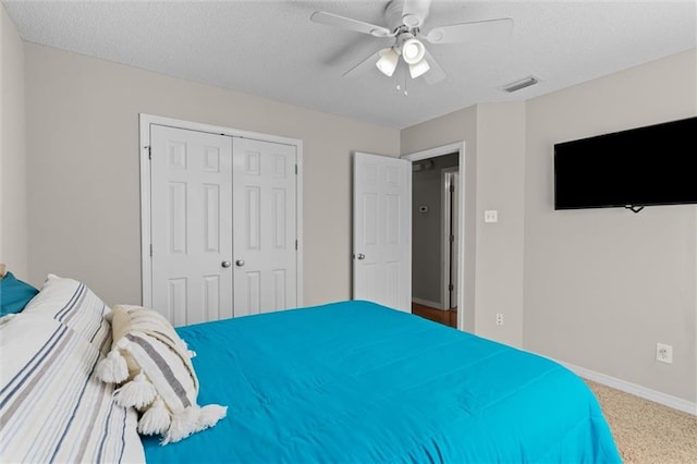 carpeted bedroom with ceiling fan, a textured ceiling, and a closet