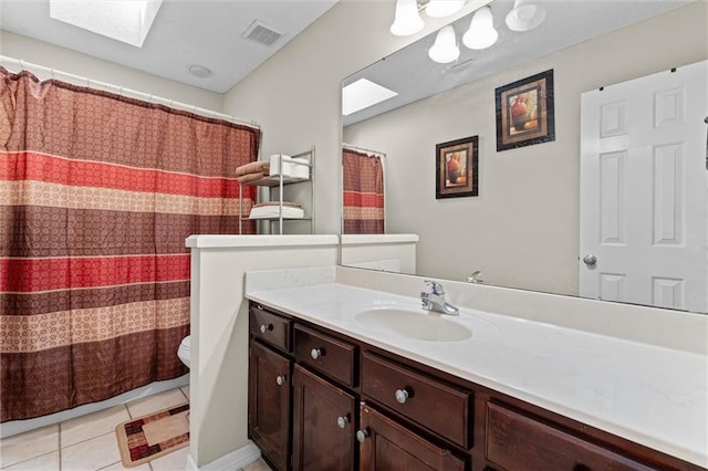 bathroom with tile patterned flooring, vanity, a skylight, and toilet