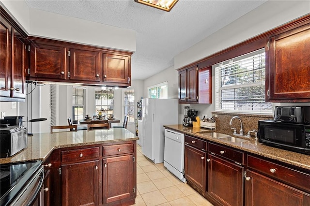 kitchen featuring a healthy amount of sunlight, dishwasher, sink, and light tile patterned flooring