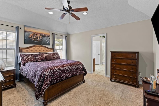 carpeted bedroom with a textured ceiling, ceiling fan, vaulted ceiling, and connected bathroom