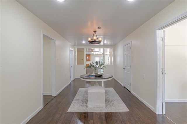 corridor featuring an inviting chandelier and dark hardwood / wood-style flooring