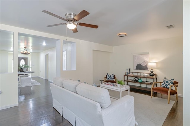 living room featuring ceiling fan with notable chandelier and dark hardwood / wood-style flooring