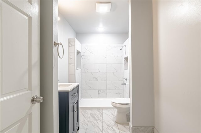 bathroom featuring vanity, toilet, and a tile shower