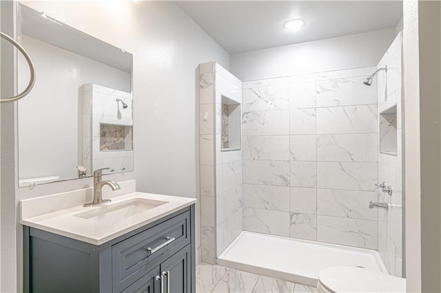 bathroom featuring vanity, toilet, and a tile shower