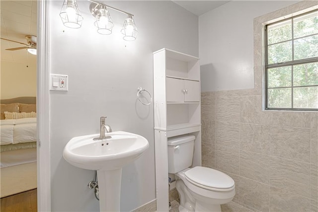 bathroom featuring tile walls, toilet, a wealth of natural light, and ceiling fan