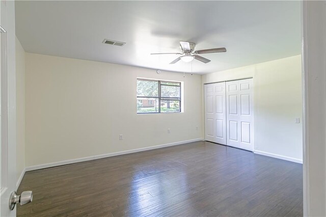 unfurnished bedroom featuring dark hardwood / wood-style flooring, ceiling fan, and a closet