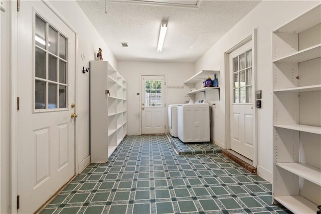 washroom with tile flooring, washer and dryer, and a textured ceiling