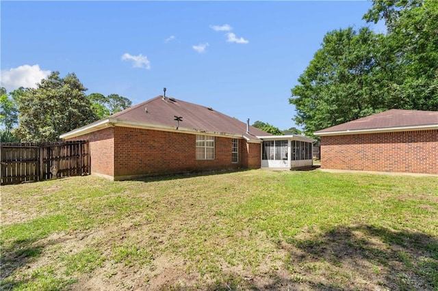 back of property featuring a sunroom and a lawn