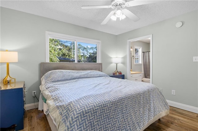 bedroom featuring ensuite bath, ceiling fan, dark wood-type flooring, and a textured ceiling