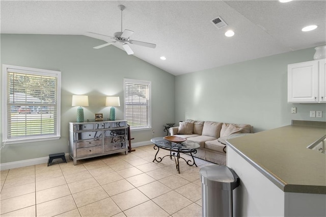 living room featuring ceiling fan, lofted ceiling, a textured ceiling, and light tile patterned floors